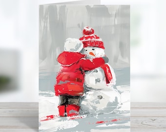 May include: A greeting card featuring an impressionistic painting of a figure in a bright red hooded coat and red boots hugging a snowman. The snowman has a carrot nose and wears a red knit hat and scarf against a grey snowy background.