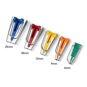 May include: Set of five colorful bias tape makers in blue, red, yellow, orange, and green. Each tool has a stainless steel frame and a plastic insert. Sizes range from 6mm to 25mm.