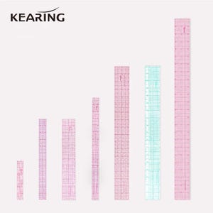 May include: A set of seven clear plastic rulers of varying lengths, each featuring a pink grid pattern and black measurement markings. The brand name KEARING is printed in black text at the top left. The rulers are arranged vertically.