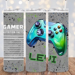 May include: A personalized gamer-themed tumbler with a teal and green controller design. The tumbler features the name "LEVI" in green pixelated letters and a "Gamer Nutrition Facts" label. The background is gray with controller outlines and black paint splatters.