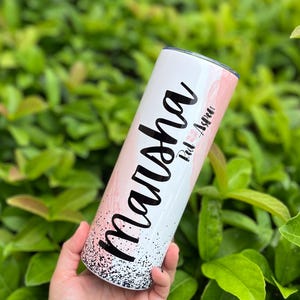 以下が含まれることがあります： 白とピンクのステンレス製のタンブラーで、黒のグリッターデザインと「Malusha」という名前と「Rad AF」というテキストが書かれています。