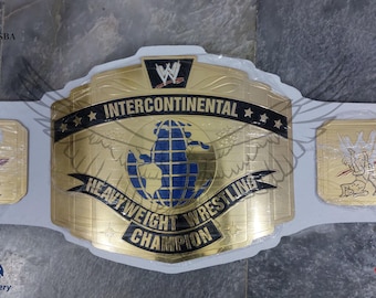 Puede incluir: Cinturón de campeón de lucha de peso pesado intercontinental dorado con un diseño de globo azul y dorado. El cinturón tiene el logotipo y el texto de la WWE, con placas rectangulares doradas adicionales.