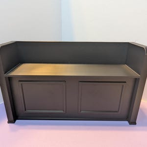 May include: A dark brown wooden bench with a back and two front panels. The bench has a simple, classic design, suitable for indoor use. The bench is approximately 48 inches wide, 18 inches deep, and 36 inches high.