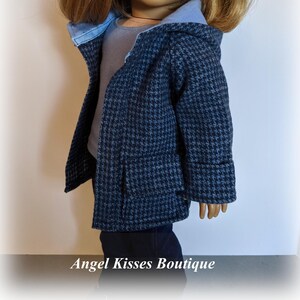 May include: A blue and white houndstooth hooded jacket with a blue lining. The jacket has a pocket on the front and is made for a doll.