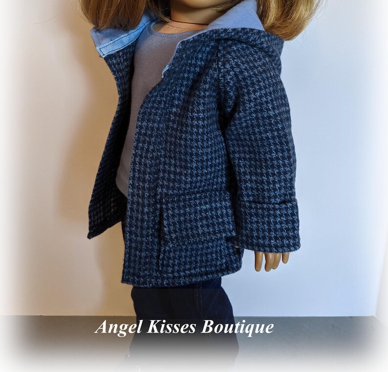 May include: A blue and white houndstooth hooded jacket with a blue lining. The jacket has a pocket on the front and is made for a doll.