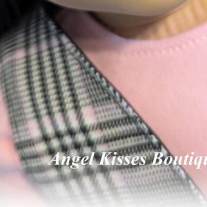 Op de afbeelding: Een close-up van een roze en witte geruite stof met een zwart-witte geruite band. De tekst "Angel Kisses Boutique" is zichtbaar in de rechterbenedenhoek van de afbeelding.