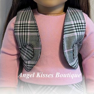 Op de afbeelding: Een zwart-wit geruit vest met roze bies en hartvormige details. Het vest wordt gedragen over een roze longsleeve. Angel Kisses Boutique.