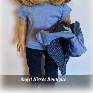 May include: A doll wearing a light blue t-shirt, dark blue jeans, and a dark blue and grey jacket.