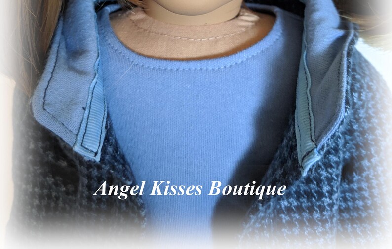 May include: A close-up of a blue shirt with a black and blue jacket. The jacket has a collar that is folded down. The text "Angel Kisses Boutique" is visible in the image.