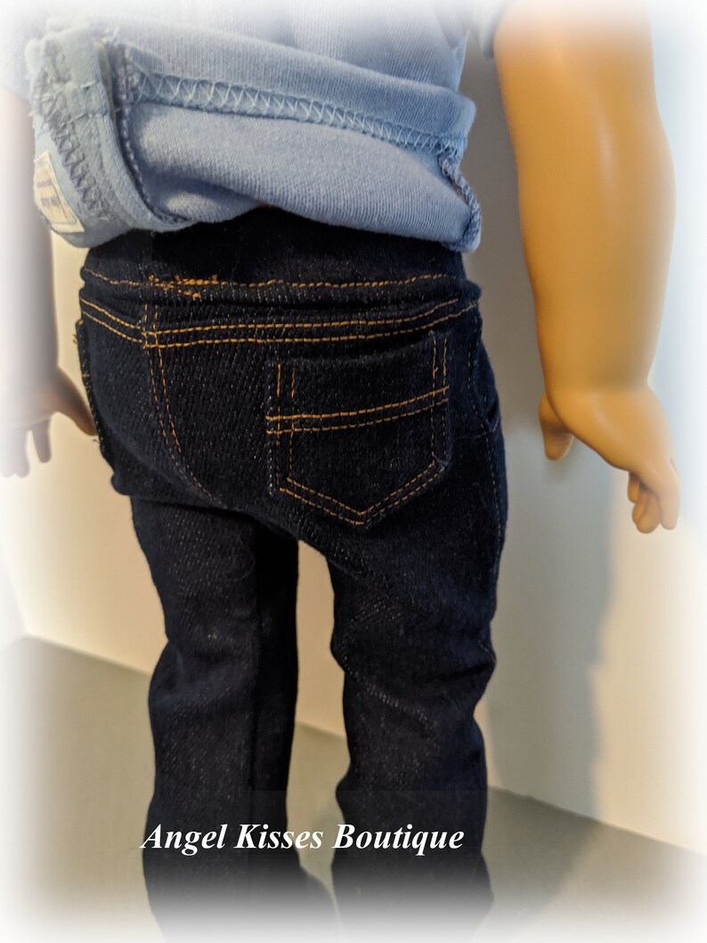 May include: A pair of dark blue denim jeans with orange stitching. The jeans have a back pocket with orange stitching.