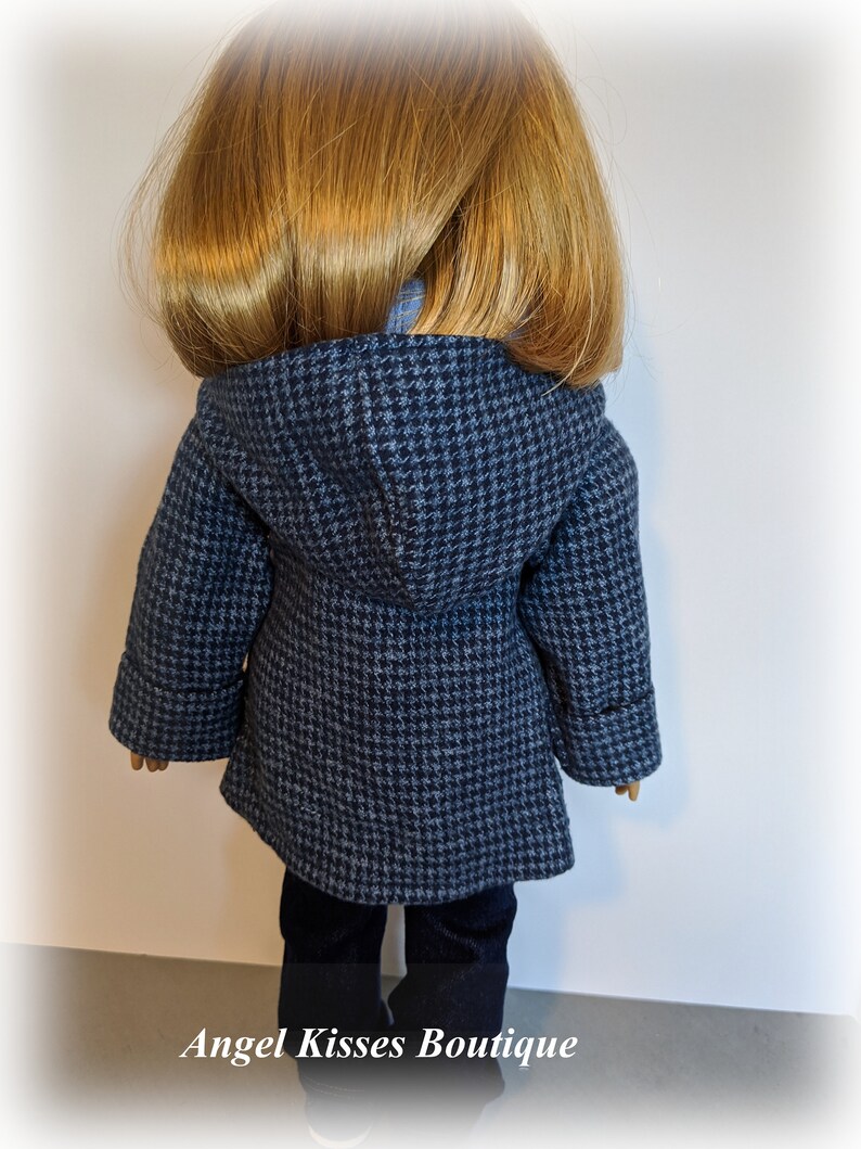 May include: A blue and white houndstooth hooded coat for a doll. The coat has long sleeves and a zip closure. The doll is wearing blue jeans.