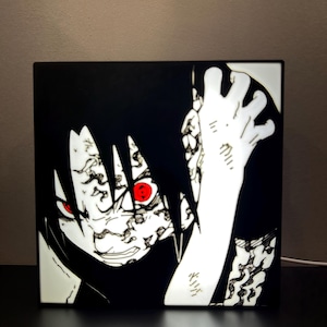 May include: Square black and white anime-style light box featuring a character with red eyes and black hair. The character's face and hand are illuminated, with intricate details and a dynamic pose. A white power cord extends from the bottom.