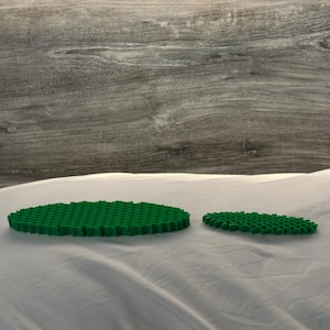 May include: Two green oval-shaped foam pads with a honeycomb pattern. The pads are on a white surface.