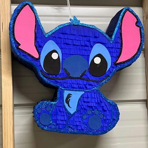 May include: Blue and pink Stitch character pinata with glitter accents.