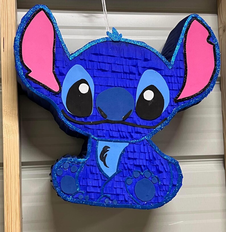 May include: Blue and pink Stitch character pinata with glitter accents.