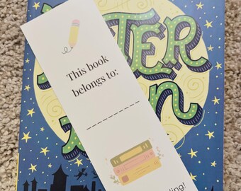 May include: A bookmark with a pencil illustration and the text "This book belongs to:" rests on a book with a starry night design. The bookmark also features a stack of books and the words "Happy Reading!"