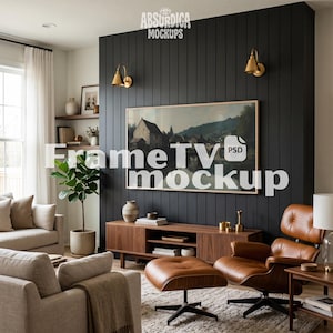 May include: A digital television display mounted on a black vertical paneled wall, showcasing a landscape painting. The setup includes a wooden media console, a brown leather lounge chair with an ottoman, and a potted plant in a living room.