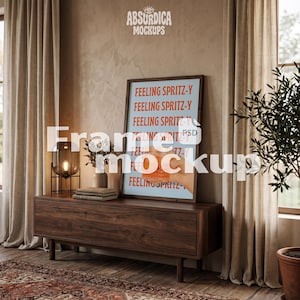 May include: A rectangular wooden frame containing a light blue poster with the repeated orange text "FEELING SPRITZ-Y" and an illustration of a hand holding a glass with an orange liquid, resting on a dark wood console table.