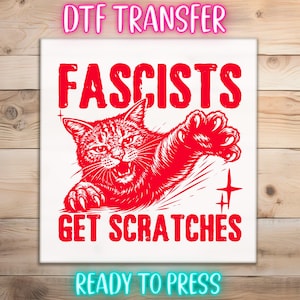 May include: A red graphic design on a white background features a cat with the text "Fascists Get Scratches." The words "DTF TRANSFER" and "READY TO PRESS" are also included. The design is suitable for heat transfer applications.