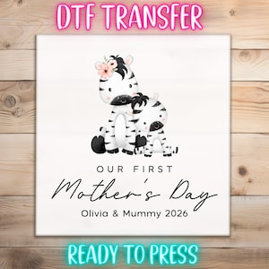 May include: DTF TRANSFER image featuring two cartoon zebras, one adult and one child, with floral accents. The text reads "OUR FIRST Mother's Day Olivia & Mummy 2026" and "READY TO PRESS".