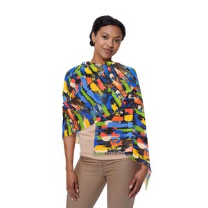 Könnte beinhalten: Ein farbenfrohes Tuch mit einem abstrakten Pinselstrich-Design in Blau, Orange, Grün und Gelb. Das Tuch ist über den Schultern drapiert und zeigt das kräftige Muster und die Fransen. Das Accessoire sorgt für einen Farbtupfer.