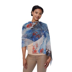 Könnte beinhalten: Blau-weißer Schal mit Aquarelldesign mit roten Blumen und einer Berglandschaft. Der Schal ist über den Schultern drapiert.