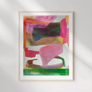 May include: A framed abstract painting featuring layered brushstrokes in vibrant shades of pink, orange, deep green, and yellow. The composition displays organic shapes and color blocks on a white background, enclosed within a light wood frame.