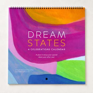 May include: A spiral-bound calendar titled DREAM STATES A CELEBRATIONS CALENDAR. The cover features abstract brushstrokes in vibrant shades of orange, magenta, purple, light pink, lime green, and blue, with white and yellow text printed centrally.