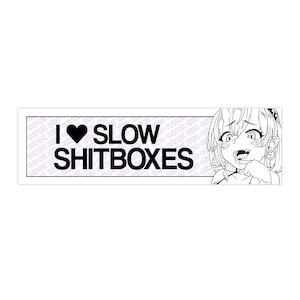 May include: A black and white sticker with the text "I ♥ SLOW SHITBOXES" in a bold font. An anime-style illustration of a girl is on the right side of the sticker. The sticker has a white border.