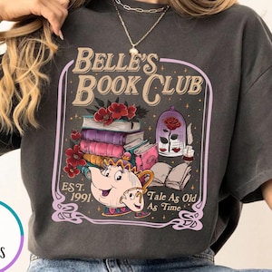 May include: Pepper-colored t-shirt featuring a graphic for Belle's Book Club. The design includes a stack of books, a teapot, a rose in a glass dome, and the text "Belle's Book Club, Est. 1991, Tale As Old As Time."