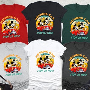 May include: A collection of t-shirts in various colors, including red, black, and white. Each shirt features a graphic of Mickey Mouse and friends in a red car, with the text "NOTHING CAN STOP US NOW!"