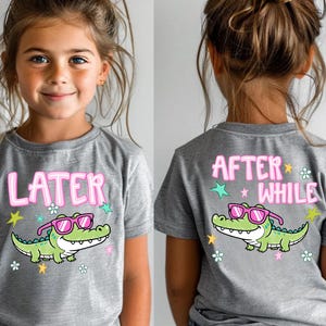 May include: Athletic heather gray t-shirt with a cartoon alligator wearing pink sunglasses. The front of the shirt says "LATER" in pink letters. The back of the shirt says "AFTER WHILE" in pink letters.