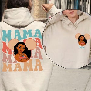 May include: Sand-colored hoodie with the word "MAMA" in a retro font on the back, along with a cartoon image of a woman. The front of the hoodie has a smaller version of the image and the name "Emily".