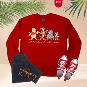 Puede incluir: Una sudadera roja con una ilustraci&oacute;n de Winnie the Pooh, Tigger, Eeyore y Piglet, con el texto "without Pooh the adventure would be impossible." La imagen incluye vaqueros azules, gafas naranjas y zapatillas rojas.