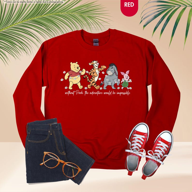 Puede incluir: Una sudadera roja con una ilustraci&oacute;n de Winnie the Pooh, Tigger, Eeyore y Piglet, con el texto "without Pooh the adventure would be impossible." La imagen incluye vaqueros azules, gafas naranjas y zapatillas rojas.