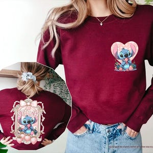 Puede incluir: Sudadera granate con gr&aacute;ficos de Stitch en la parte delantera y trasera. La parte delantera presenta a Stitch en un coraz&oacute;n. La parte trasera tiene a Stitch en un marco decorativo con la palabra "Stitch".