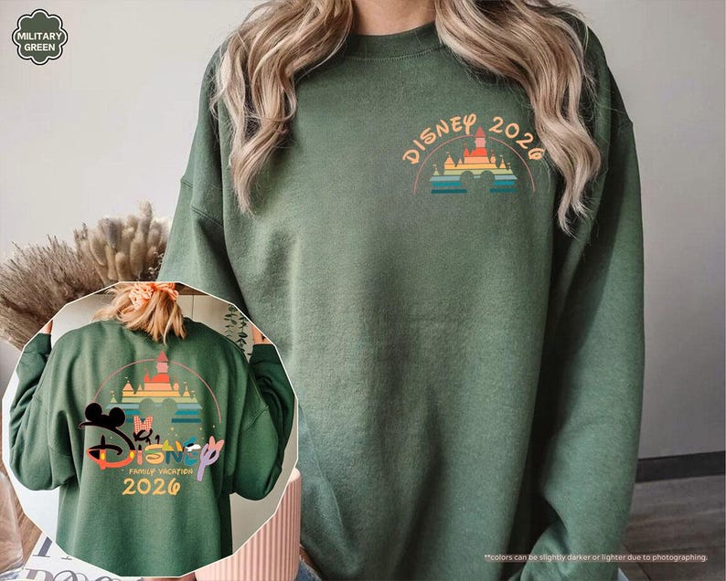 May include: Military green sweatshirt with a colorful Disney castle graphic and the text "DISNEY 2026" on the front. The back of the sweatshirt features a larger graphic with Mickey and Minnie Mouse, the text "FAMILY VACATION 2026", and the Disney logo.