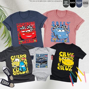 May include: A collection of t-shirts and a baby onesie with characters from the Cars movie. Designs feature Lightning McQueen, Sally Carrera, Guido, Doc Hudson, and Cruz Ramirez. Each item has a Route 66 graphic.