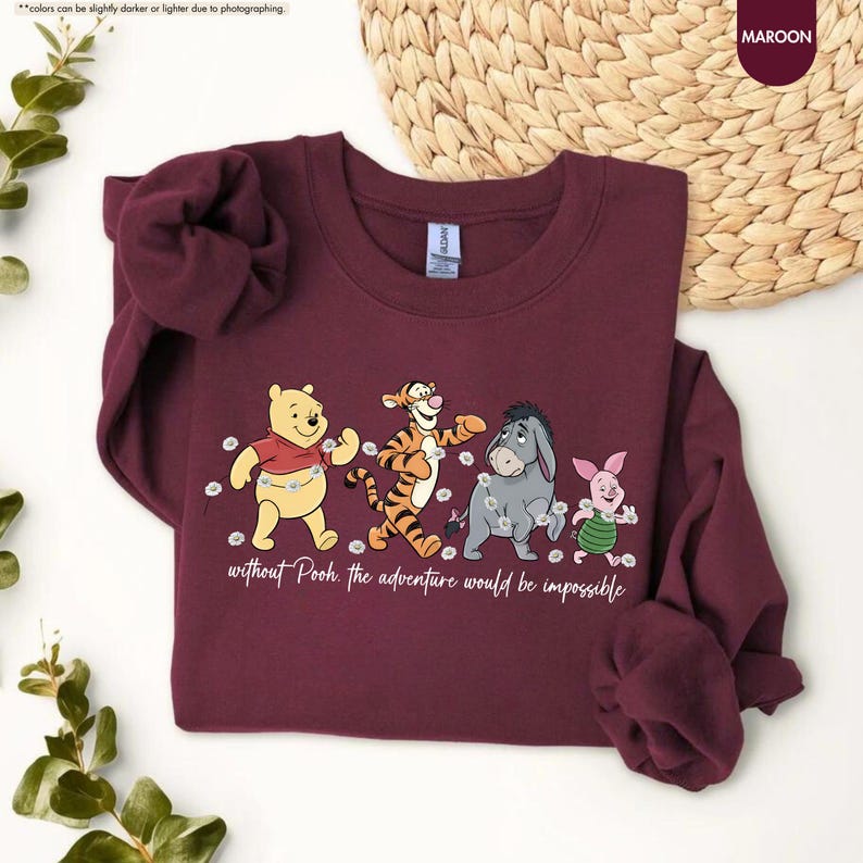 Puede incluir: Sudadera granate con una ilustraci&oacute;n de Winnie the Pooh y sus amigos. El dise&ntilde;o incluye a Pooh, Tigger, Eeyore y Piglet, con el texto "without Pooh the adventure would be impossible". Cuello redondo y mangas largas.