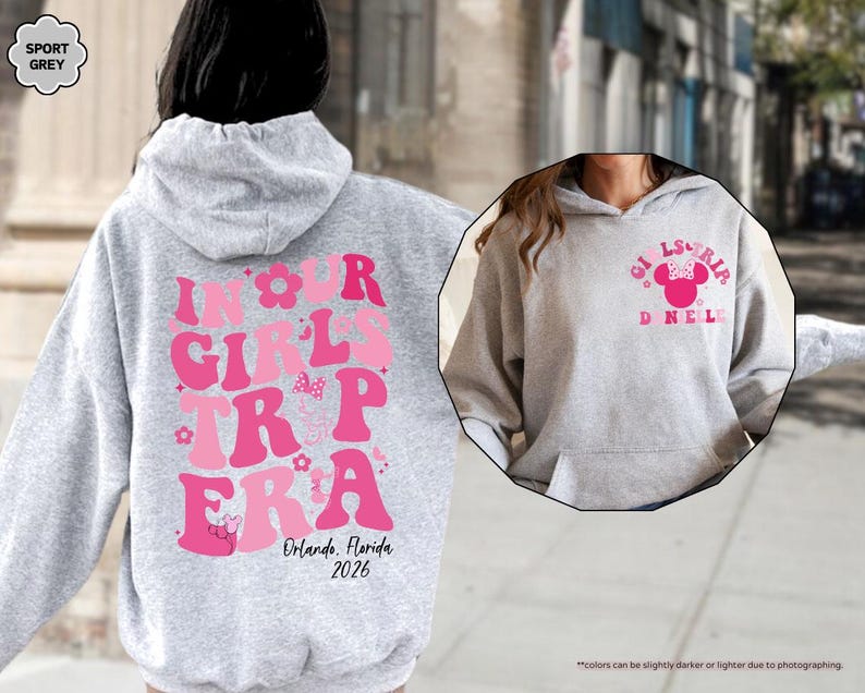 Peut inclure: Un sweat &agrave; capuche gris clair avec du texte rose qui dit "IN OUR GIRLS TRIP ERA" avec "Orlando, Florida 2026" en dessous. Le devant du sweat &agrave; capuche a un motif Minnie Mouse avec "GIRLS TRIP DNEL" en rose. Le sweat &agrave; capuche est de couleur gris sport.