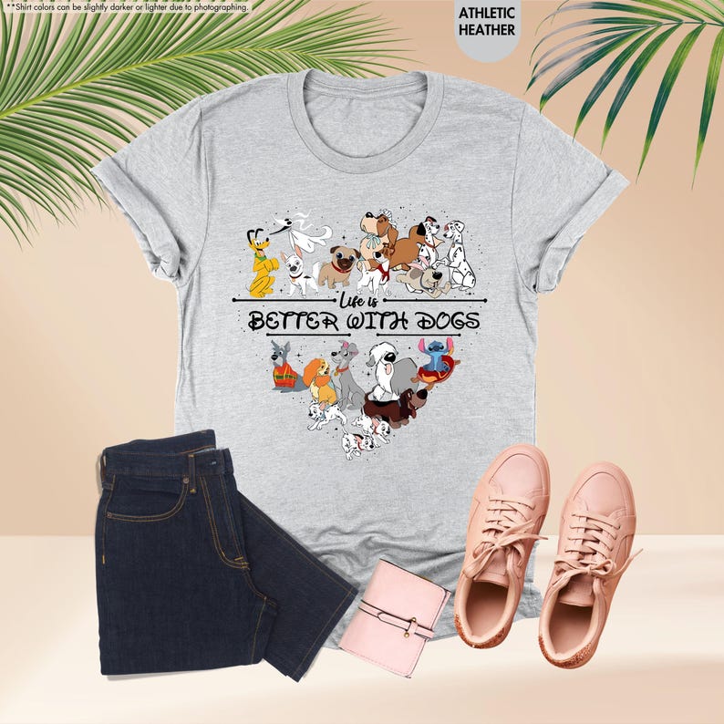 May include: A gray t-shirt with a heart-shaped design of various cartoon dogs and the text "Life is Better With Dogs." The shirt is paired with dark blue jeans, pink sneakers, and a small pink wallet.