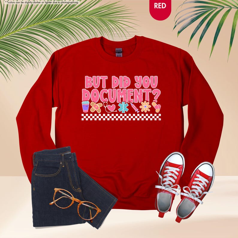 Puede incluir: Una sudadera roja con el texto "BUT DID YOU DOCUMENT?" en rosa y blanco, con gr&aacute;ficos de tem&aacute;tica m&eacute;dica. La imagen tambi&eacute;n muestra unos vaqueros azules, gafas con montura dorada y zapatillas rojas.
