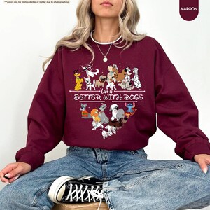 May include: Maroon sweatshirt with the text "Life is Better With Dogs" and a graphic of various cartoon dogs. The sweatshirt is a solid maroon color and has a crew neck. The graphic is in white and features several dog breeds.