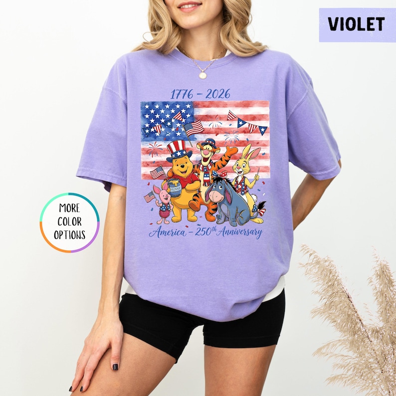 May include: Violet t-shirt featuring a graphic of Winnie the Pooh and friends celebrating the 250th anniversary of America. The design includes an American flag and the text "1776-2026" and "America - 250th Anniversary".