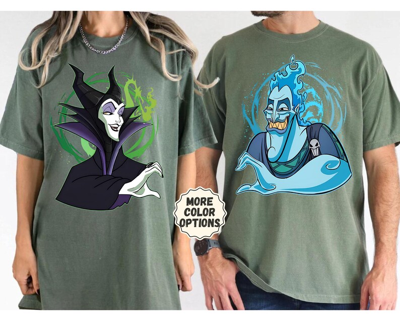 Puede incluir: Dos camisetas verde oliva con personajes de dibujos animados. Una camiseta muestra a Mal&eacute;fica en negro y morado, la otra a Hades en azul. Las camisetas tienen una pegatina "More Color Options".
