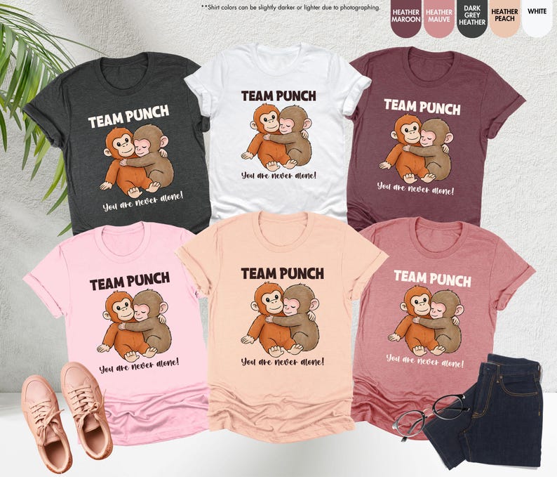 May include: A collection of t-shirts in various colors, including heather gray, white, and pink. Each shirt features the text "TEAM PUNCH" above an illustration of two hugging monkeys, with the phrase "You are never alone!" below.