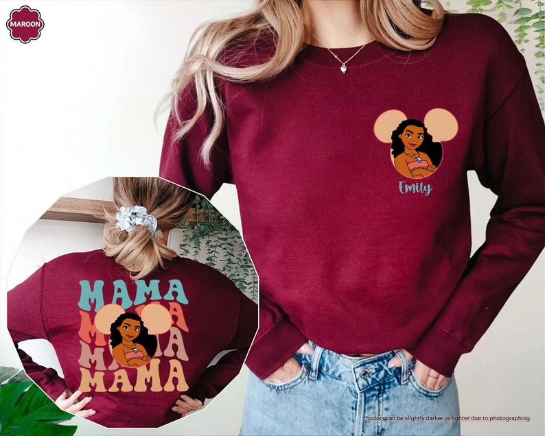 May include: Maroon sweatshirt featuring a cartoon character design with the name "Emily" below. The back of the sweatshirt displays the word "MAMA" in a layered design. The sweatshirt is made of a soft material.