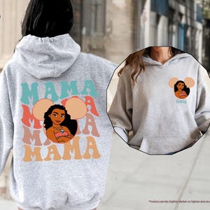 May include: A light gray hoodie with a graphic of a cartoon woman and the word "MAMA" in teal, coral, and orange. The design includes a cartoon image of a woman with the word "MAMA" repeated. The hoodie also has a small graphic on the front.