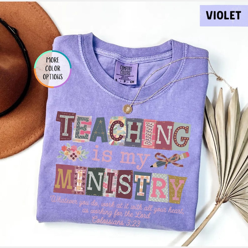 Pu&ograve; includere: Una maglietta viola Comfort Colors con le parole "TEACHING is my MINISTRY" in lettere a blocchi colorate. La maglietta presenta anche il testo "Whatever you do, work at it with all your heart as working for the Lord Colossians 3:23". Una collana d'oro &egrave; drappeggiata sulla maglietta.