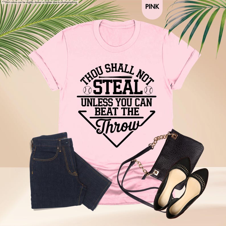 May include: Pink t-shirt with the text "Thou Shall Not Steal Unless You Can Beat The Throw" in black. The shirt is paired with dark blue jeans, a black purse, and black flats.